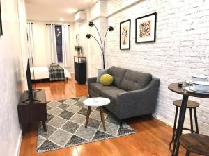 Cozy Studio Chinatown! Location! في نيويورك: غرفة معيشة مع أريكة وجدار من الطوب