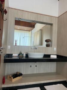 a bathroom with a sink and a large mirror at Zatara's Lodge - Monte Verde MG in Camanducaia