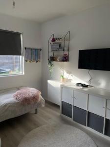 a bedroom with a bed and a desk with a tv at A cozy home away from home in Hveragerði