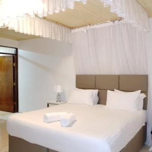 een slaapkamer met een wit bed en 2 handdoeken bij Sofitel Executive 3 bedrooms milimani in Kisumu