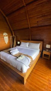 ein Schlafzimmer mit einem großen Bett in einem Holzzimmer in der Unterkunft La Cascata Bali Munduk in Munduk