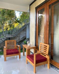 2 Stühle und ein Tisch auf einer Veranda in der Unterkunft La Cascata Bali Munduk in Munduk