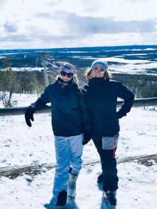 dos personas están de pie en la nieve en Levi Holiday home Poroileville, en Kittilä