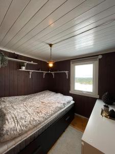 1 dormitorio con 1 cama en una habitación con ventana en Orretuen, en Austevoll