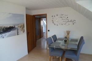 ein Esszimmer mit einem Tisch und Stühlen sowie einer Uhr an der Wand in der Unterkunft Ferienwohnung Robbe in Cuxhaven