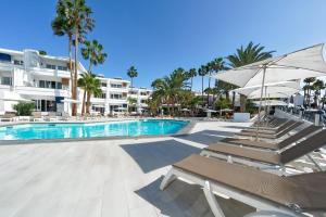 einen Pool mit Stühlen und Sonnenschirmen in einem Resort in der Unterkunft One bedroom with pool at 500m from Playa Chica, Puerto del Carmen in Puerto del Carmen