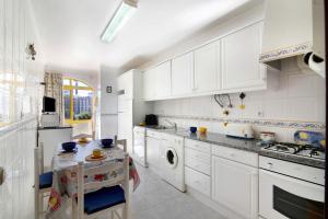 a kitchen with white cabinets and a table in it at Vila Mar Azul in Quarteira