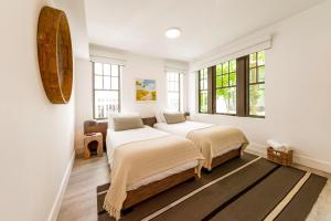 2 łóżka w pokoju z białymi ścianami i oknami w obiekcie Casa Sofi w Miami Beach