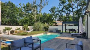a backyard with a swimming pool with chairs and a patio at Chambre au calme océan lac foret avec piscine au sel et spa in Hourtin