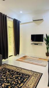 sala de estar con TV y alfombra en Kaklah Cherang Homestay en Kota Bharu