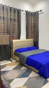 a bedroom with a bed with blue sheets and curtains at Kaklah Cherang Homestay in Kota Bharu