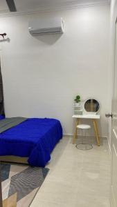 a bedroom with a blue bed and a table and a heater at Kaklah Cherang Homestay in Kota Bharu