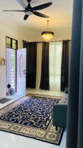 a living room with a child playing in the front door at Kaklah Cherang Homestay in Kota Bharu