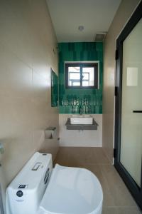 a bathroom with a white toilet and a green wall at Dk House Hue in Hue