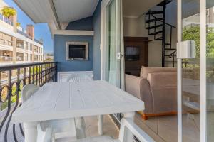 a balcony with a white table and a couch at Excelente Apartamento 190m da Praia de bombinhas - 3 dorms 6 pessoas in Bombinhas
