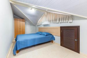 a bedroom with a blue bed and a window at Excelente Apartamento 190m da Praia de bombinhas - 3 dorms 6 pessoas in Bombinhas