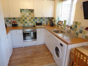 a kitchen with a sink and a washing machine at Pump Lodge in Weymouth