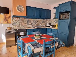 une cuisine avec des placards bleus et une table avec des chaises dans l'établissement Vacances Et Weekends A Ceret, à Céret