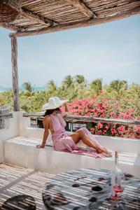 une femme en robe rose et chapeau assise sur un livre dans l'établissement LunArena Boutique Beach Hotel Yucatan Mexico, à El Cuyo