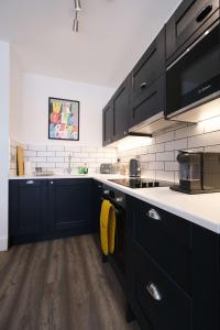 una cucina con armadi neri e ripiani bianchi di Brand New Ground Floor Apartment with Balcony a Londra