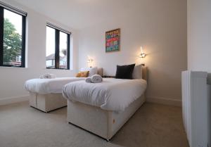 2 letti in una camera con 2 finestre di Brand New Ground Floor Apartment with Balcony a Londra