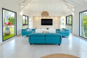 een woonkamer met blauwe banken en een tv bij Villas Vista Del Mar in Sainte-Anne