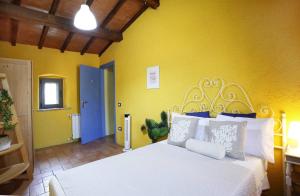 a bedroom with a white bed with a yellow wall at Villa Relax a 2 Piani e Giardino Privato con Vista sulle Colline Umbre in Piloni
