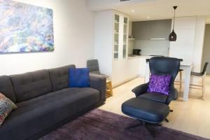 a living room with a couch and a chair at Modern Spacious 2BD2Bath - Stunning City Views! in Melbourne