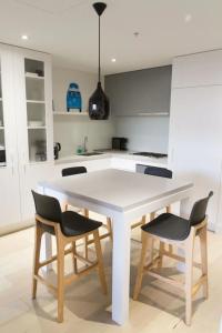 a white kitchen with a white table and chairs at Modern Spacious 2BD2Bath - Stunning City Views! in Melbourne