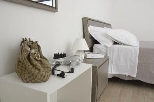 Baia Dell'Orso في توري ديل أورسو: غرفة نوم بسرير مع هاتف وحقيبة