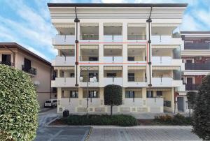 ein weißes Gebäude mit einem Parkplatz davor in der Unterkunft Gaia Apartment un gioiello in Grado