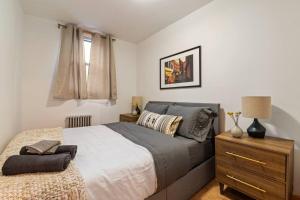 a bedroom with a bed and a dresser with a lamp at Delightful 2BR Apartment in NYC! in New York