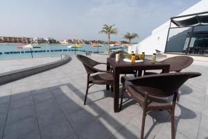 a table and chairs next to a swimming pool at La Fontaine Lagoon Resort in Durat Alarous