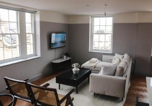 a living room with a couch and a table and two windows at Bath Street Penthouse in Bath