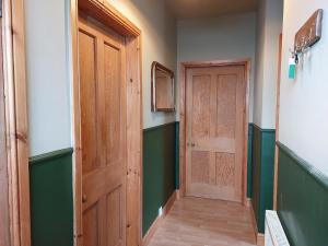 a hallway with a wooden door and green walls at Cosy flat in Innerleithen in Innerleithen