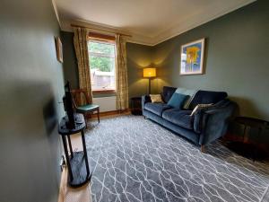 sala de estar con sofá azul y ventana en Cosy flat in Innerleithen en Innerleithen