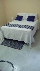 uma grande cama branca com almofadas azuis num quarto em Mosas Home em Serowe