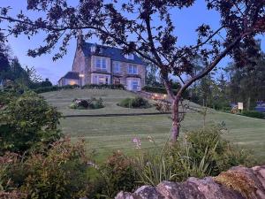 a large house sitting on top of a lush green field at The Poplars Guest House in Pitlochry