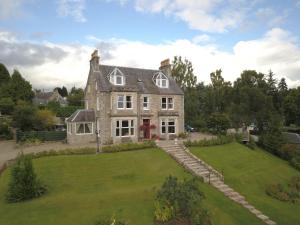 a large stone house with a large yard at The Poplars Guest House in Pitlochry