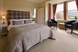 a bedroom with a large bed and chairs and windows at The Poplars Guest House in Pitlochry