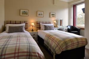 a bedroom with two beds and a desk and a chair at The Poplars Guest House in Pitlochry