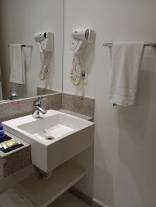 ein Badezimmer mit einem weißen Waschbecken und einem Spiegel in der Unterkunft Linhares Design Hotel in Linhares