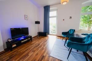 ein Wohnzimmer mit blauen Stühlen und einem Flachbild-TV in der Unterkunft Blue Chili 04 - MD Top City Apartment - WiFi in Magdeburg