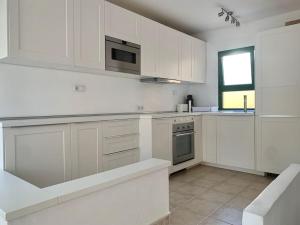 a white kitchen with white cabinets and a window at Casa Fra - su 2 piani, confortevole e accogliente, Wi-Fi, piscina in Costa Calma