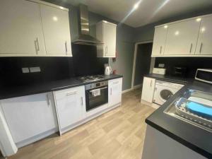 a kitchen with white cabinets and a black counter top at Silver Stag Properties, 4 BR Perfect for Groups in Hugglescote