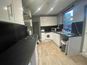 a kitchen with white cabinets and a black counter top at Silver Stag Properties, 4 BR Perfect for Groups in Hugglescote