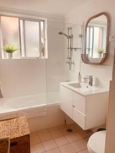 a white bathroom with a sink and a mirror at Top Mosman Location in Sydney