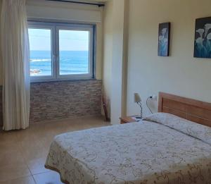 Un dormitorio con una cama con vista al mar. en BeiramarApartamento, en Muxía