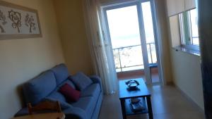 Una sala de estar con un sofá azul y una mesa. en BeiramarApartamento, en Muxía