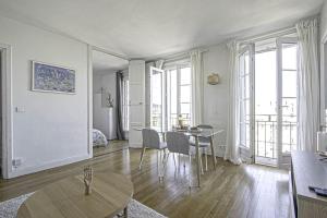 uma sala de estar branca com uma mesa e cadeiras em F2 immeuble Perret avec vue à 180 ° sur la ville - Parking privatif - Hypercentre em Le Havre